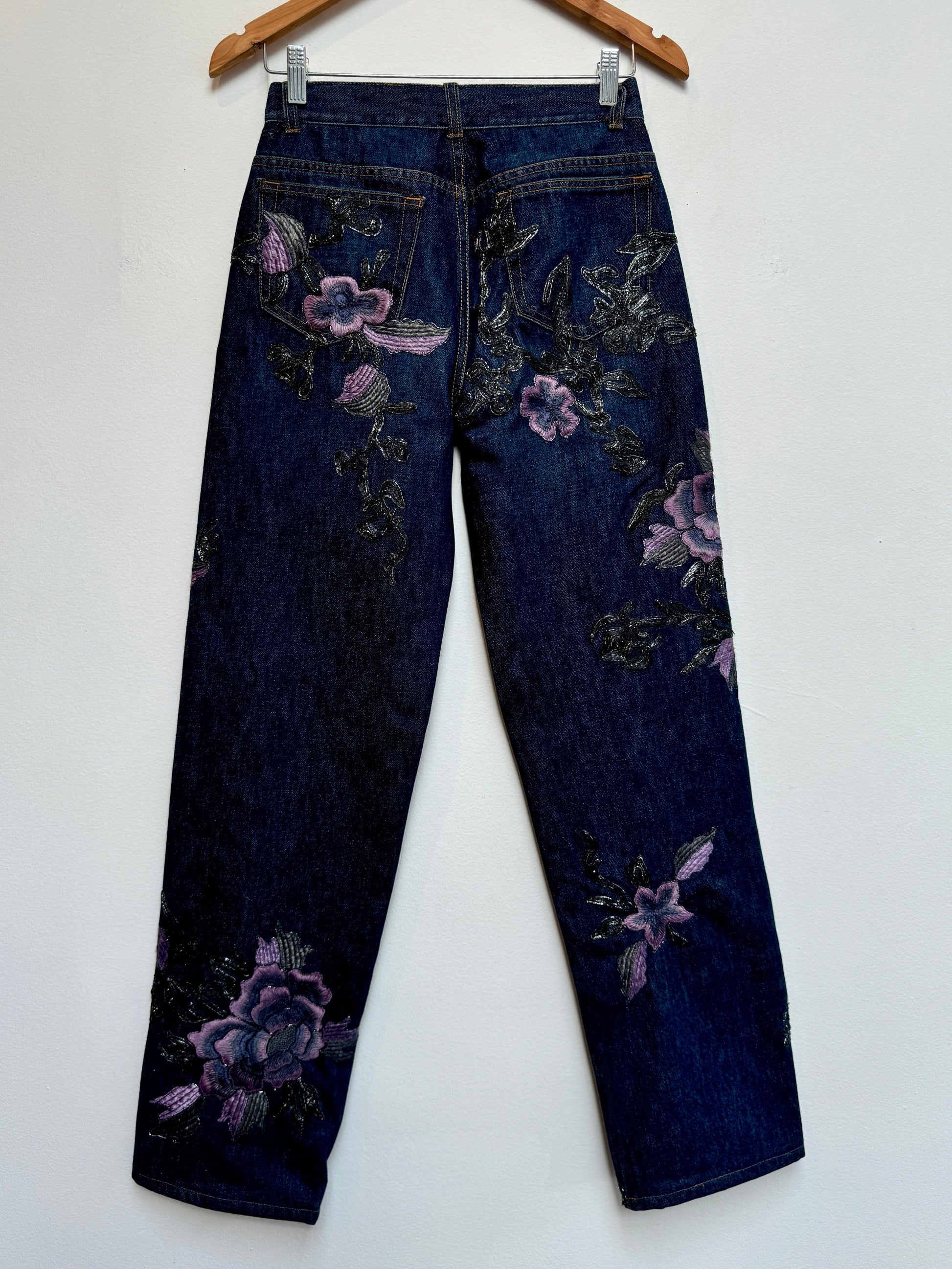 Denim jeans with metallic soutache embroidery and purple flowers.