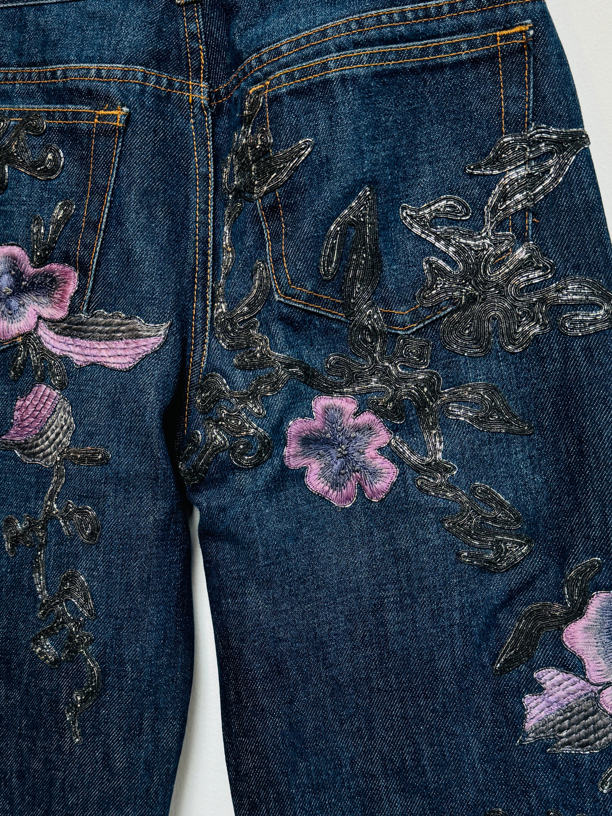 Denim jeans with metallic soutache embroidery and purple flowers.