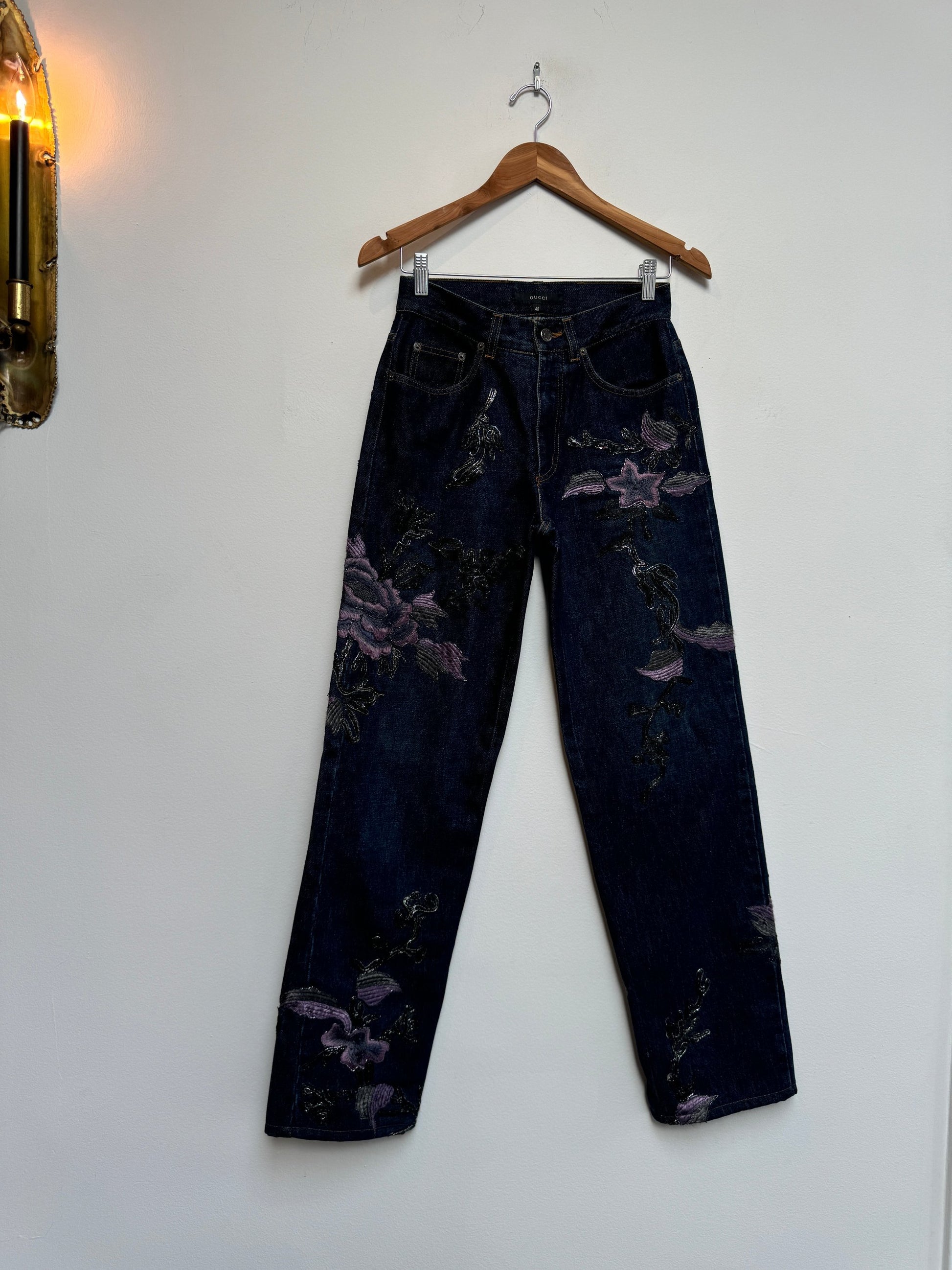 Denim jeans with metallic soutache embroidery and purple flowers.